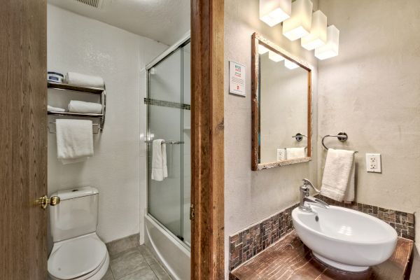 A clean bathroom with a shower, toilet, and sink area with a mirror and modern lighting above.